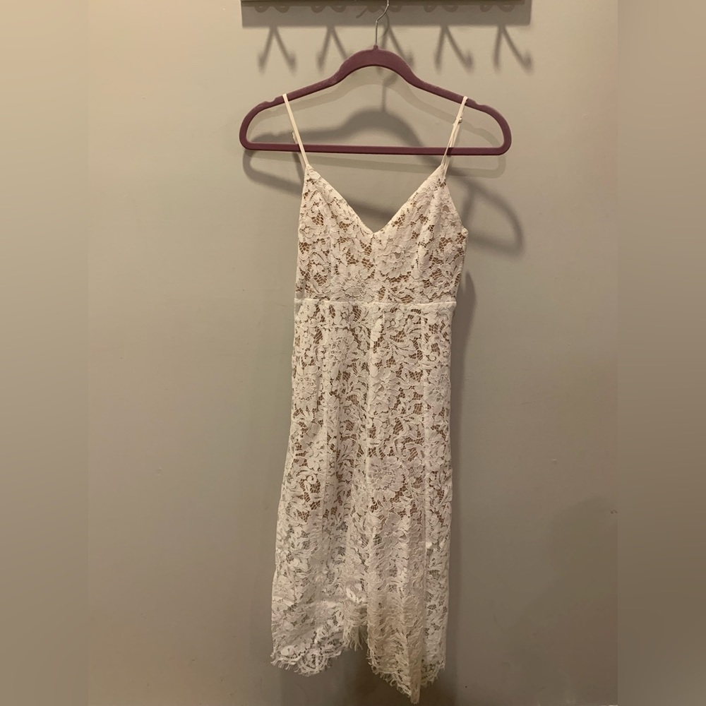 White lace dress with handkerchief hem and adjustable straps.